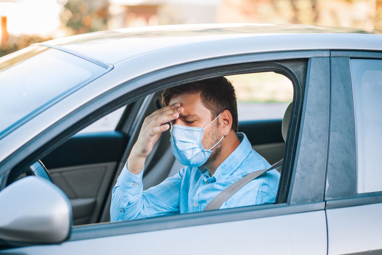 man wearing mask in his car after an accident